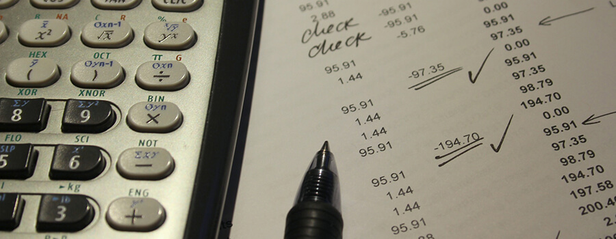Close up image of calculator printed accounts and pen.