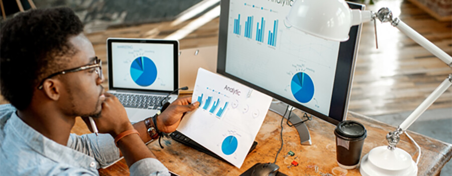 Man analysing data on screen and on paper.