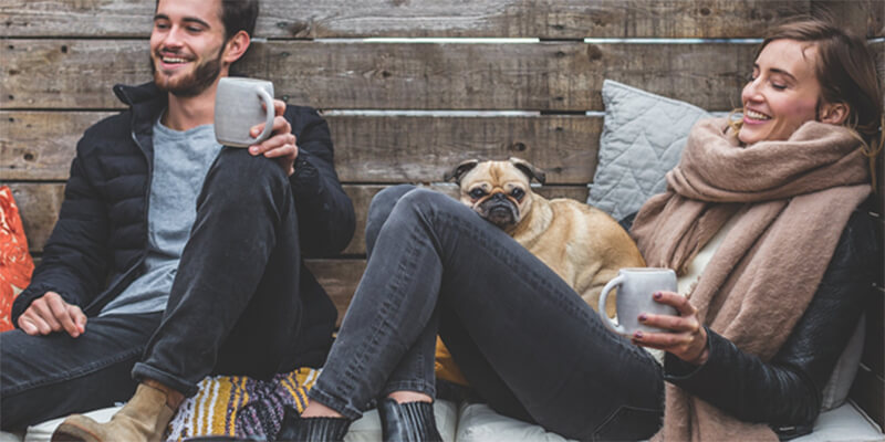 Young couple relaxing with hot drinks and a pug.