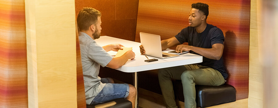 Two people having a meeting an a booth.