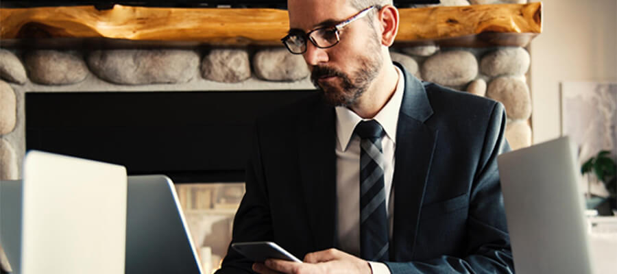 Man in suit using laptop and phone.