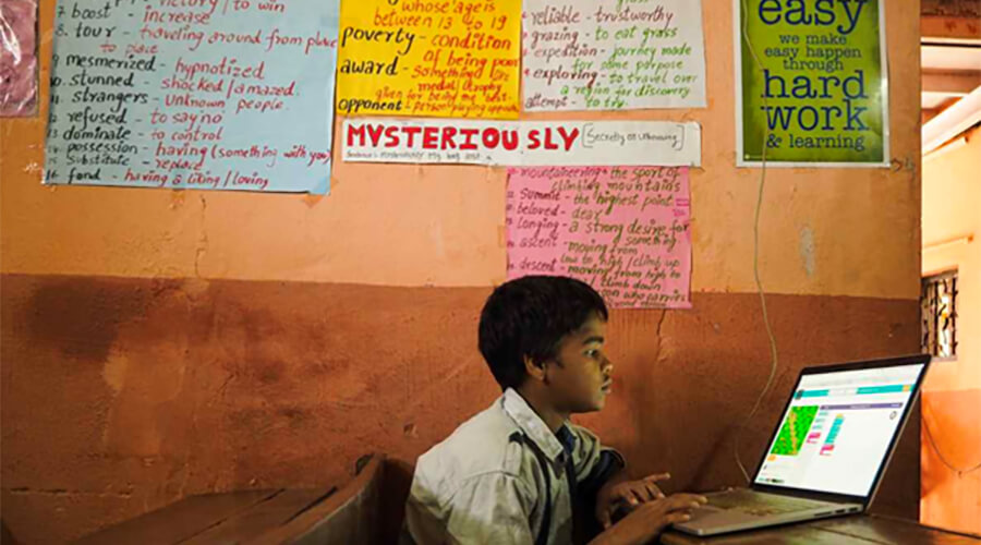 Child doing schoolwork on a laptop in classroom.