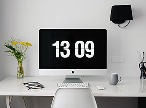 A screen in a home office with a big clock.