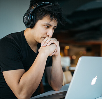 Man with headphones focused on laptop screen.