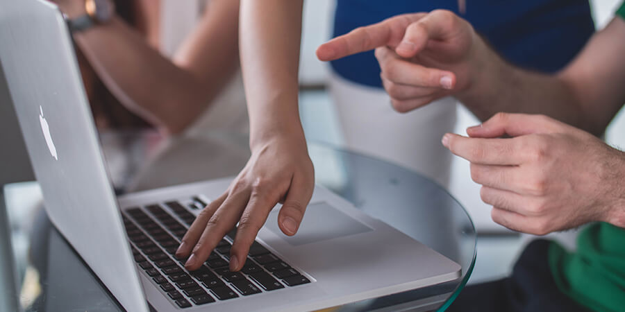 Close up of hands and arms working on a laptop.