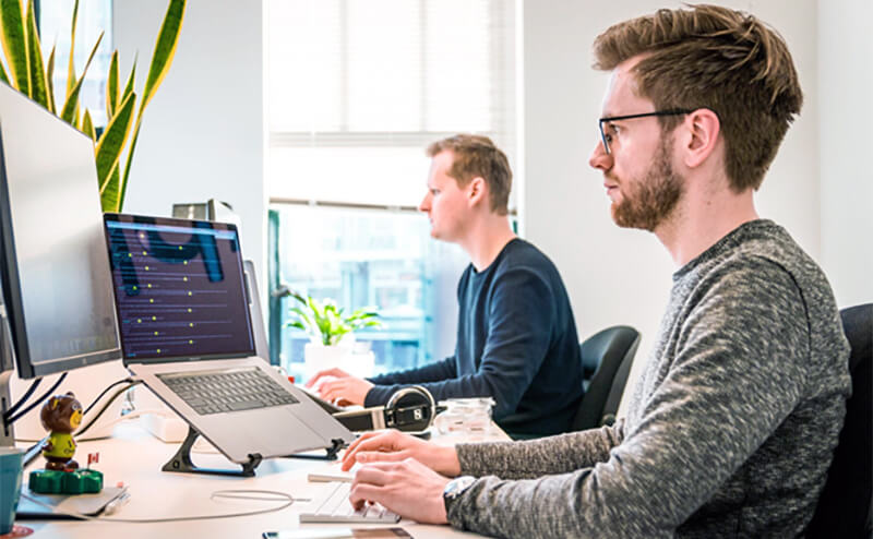 Two people working on computers in an office.