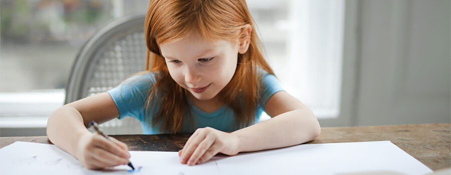 Young girl drawing on paper at home.