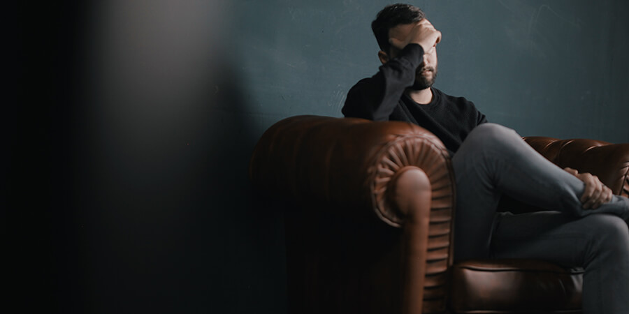 Man sitting in a leather chair with his hand over his face.