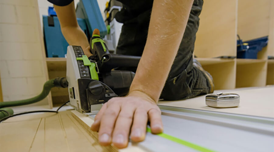 A handyman using a circular saw to cut a piece of wood.