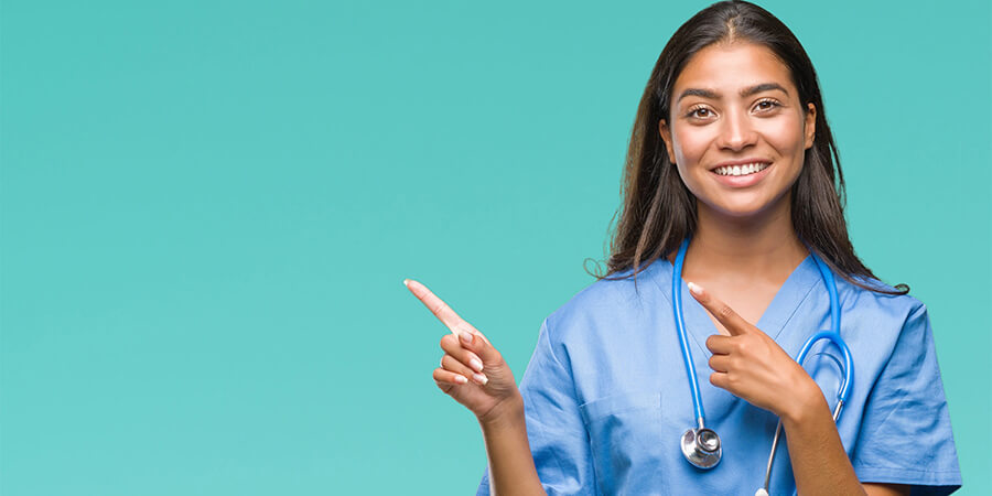 A nurse wearing scrubs and smiling.