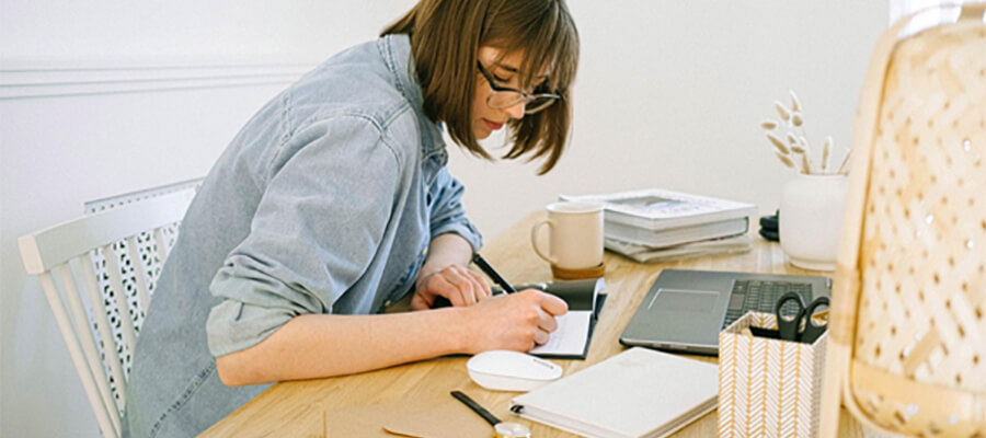 Woman writing in a notebook. Working at home.