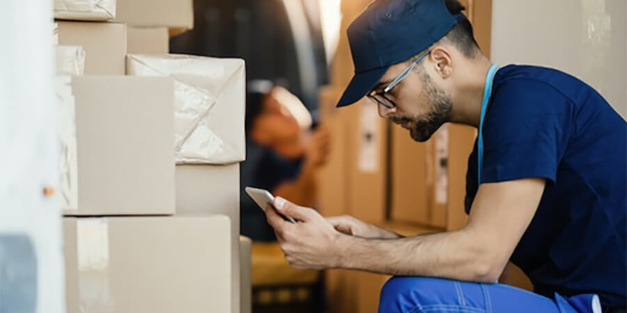 Logistics worker looking on tablet next to a stack of boxes.
