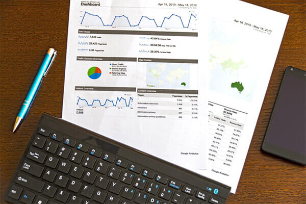 Desktop with laptop and printed analytics data.