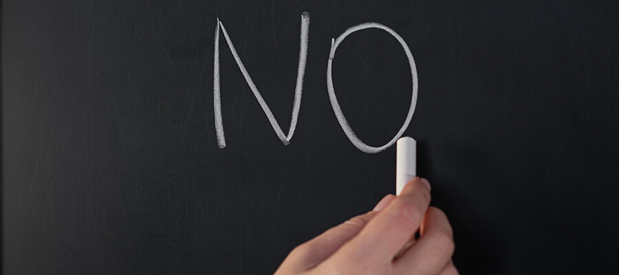 Hand writing no on a blackboard with chalk.