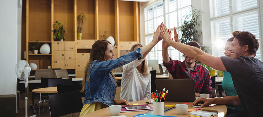 Group of young people in the office giving a high-five.