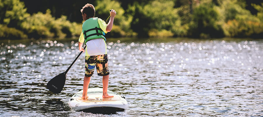 Teenager paddleboarding on a lake.