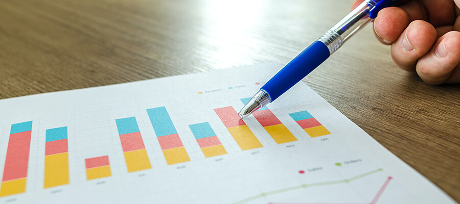 Using a pen to point to a bar chart on a sheet of paper.