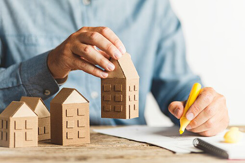 Male hand holding a model of a house.