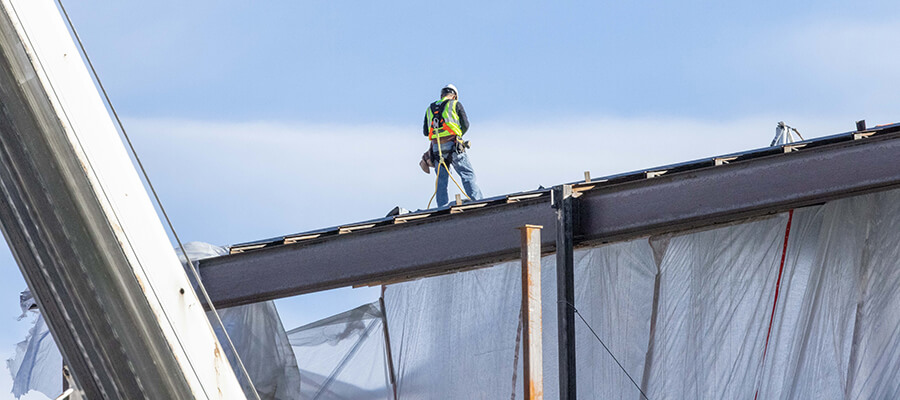 Roofer standing on top of a metal structure.