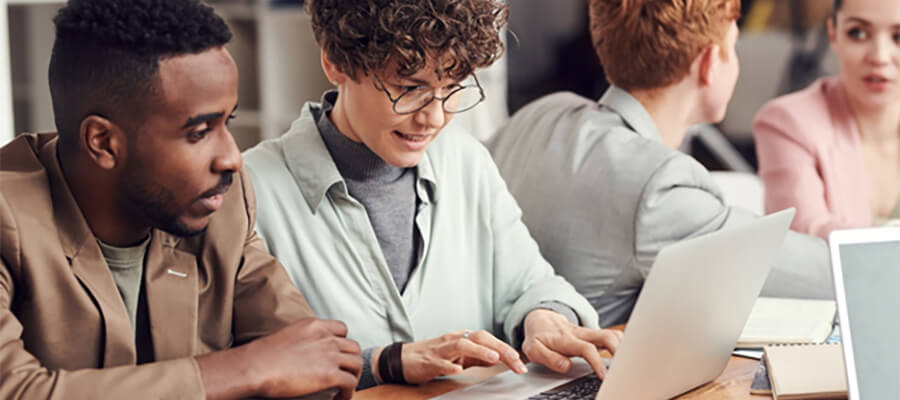 Group of young people looking at a laptop.