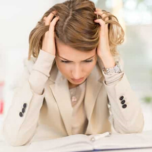 Woman with her head in her hands looking down at an open book.