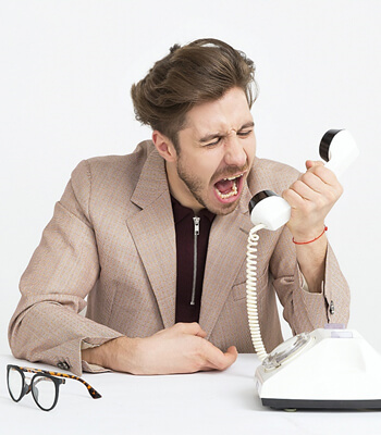 Man shouting down a landline phone.