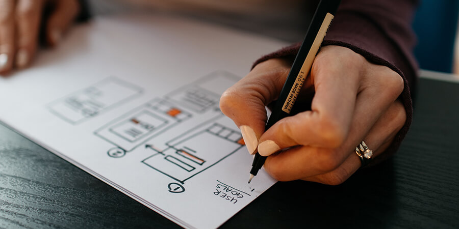 Person drawing a flowchart with a pen and paper.