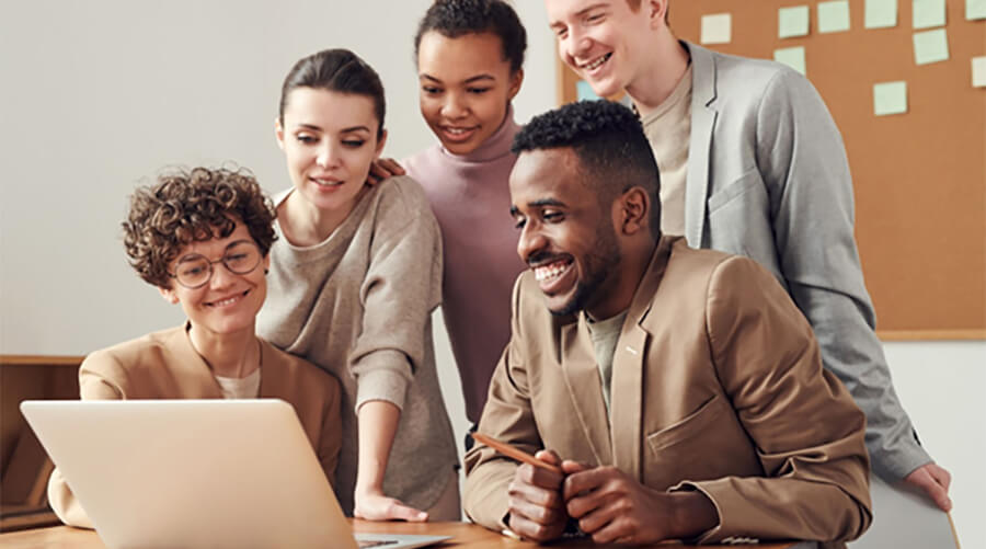 Group of people smiling at a laptop.