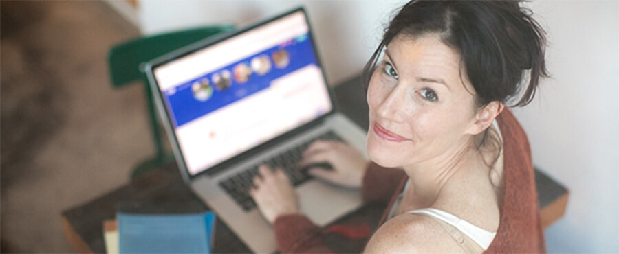 Smiling woman looking up from her laptop.