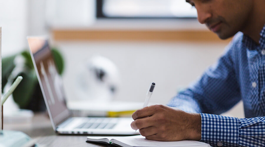 Man studying and writing in a notebook.