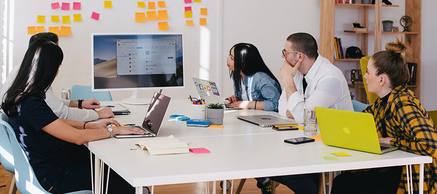 Marketing team working around a large table looking at a monitor.