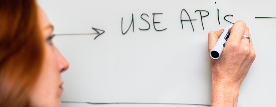 Female writing 'USE APIs' on a whiteboard.