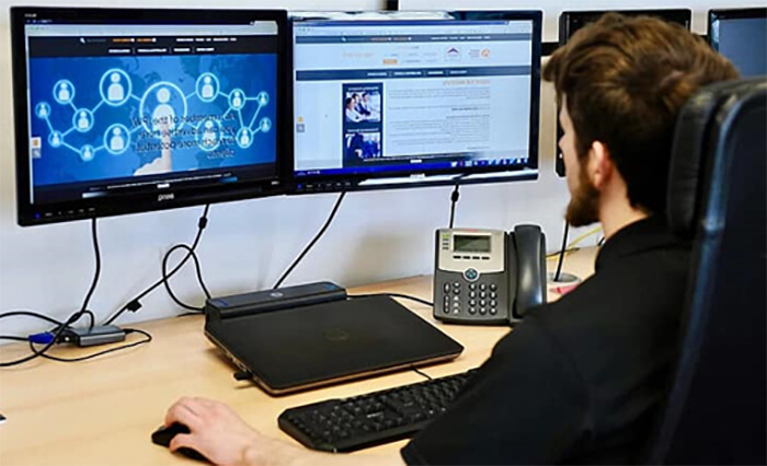 Web designer sitting at desk with two computer monitors.