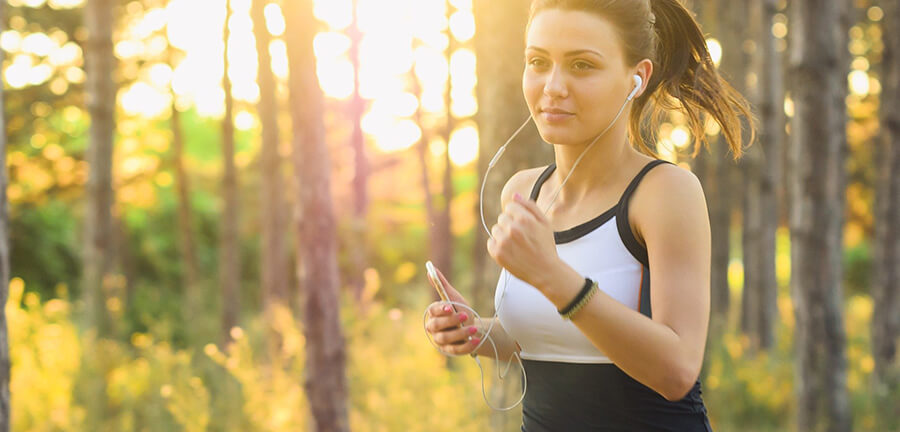 Woman jogging in the woods with headphones.