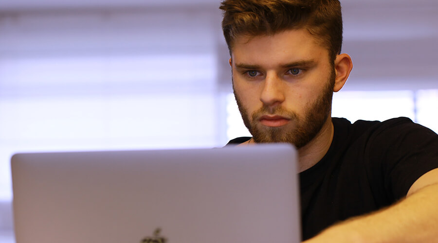 Close up of young man using a laptop.